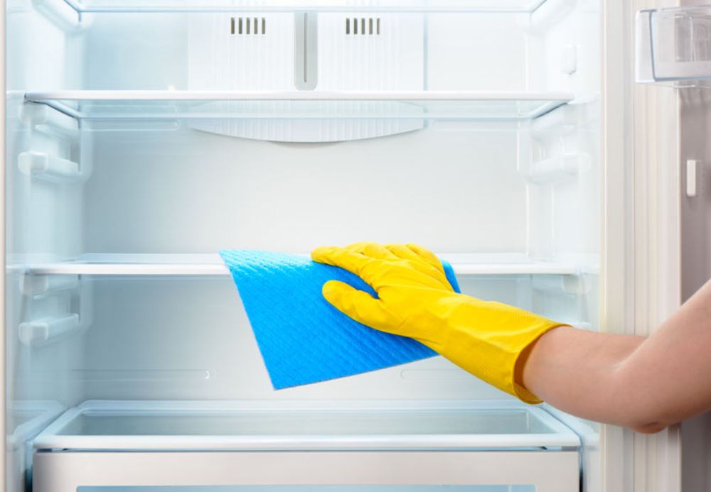 Main gantée nettoyant l'interieur d'un refrigerateur