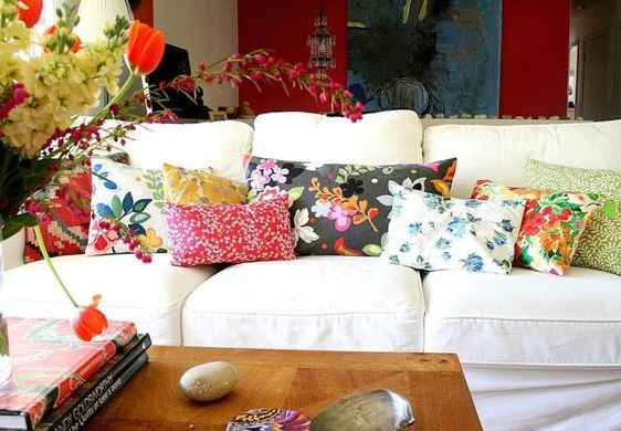 Melange de coussins sur canape avec des motifs floraux differents