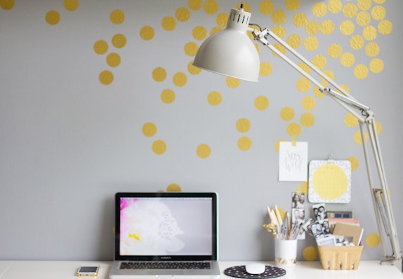 Ronds dorés collés sur un mur gris devant un bureau
