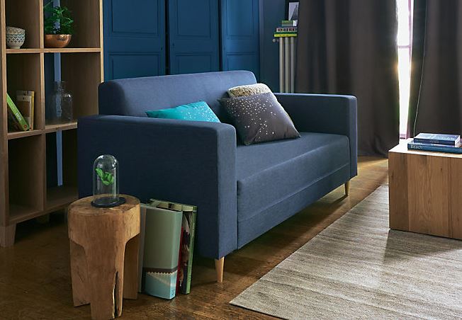 Bout de canapé en teck massif poncé à droite d'un canapé bleu