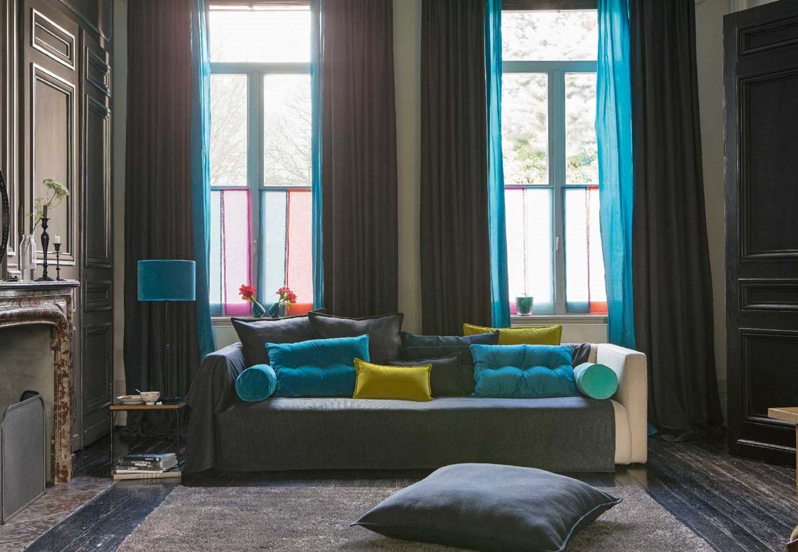 Salon sombre avec rideaux et coussins de couleurs vives