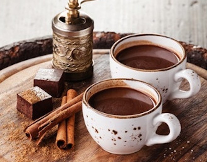 Deux tasses de chocolat chaud avec brownies et batons de canelle