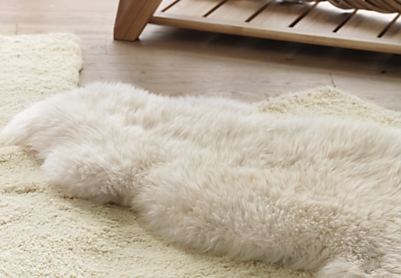 Zoom sur une peau de mouton disposée sur un tapis laineux blanc