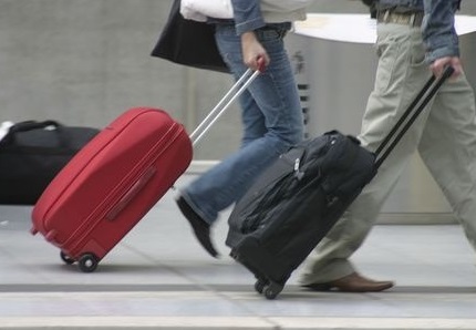 Deux personnes tirant des bagages, une valise noire et une rouge